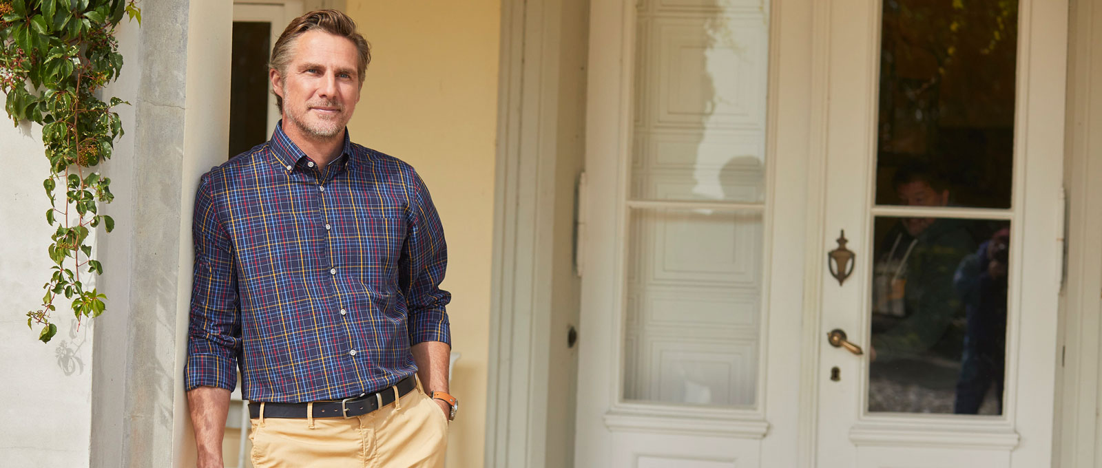 Mann in Karohemd lehnt an Tür